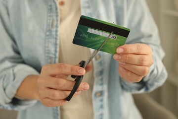 Woman cutting plastic credit card indoors, closeup