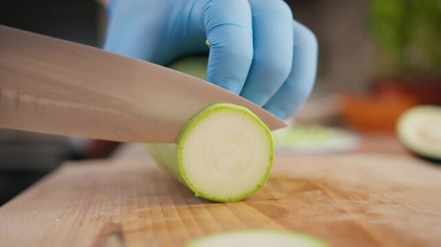 Chef Cuts Zucchini Vegetable On A Wooden Cutting Board In Restaurant Kitchen