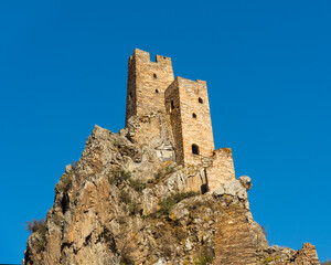 Fototapeta premium old Ruined Military Tower of Vovnushki in Ingushetia, Russia blue background sky