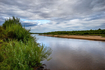 river on the background of banks with greenery and blue sky with clouds