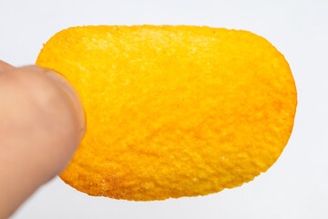 A hand holding a yellow snack