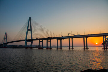 The sunset and view of Shantou Queshi Bridge at Xidi Park Shantou China is a breathtaking sight. As the sun dips below the horizon, the sky transforms into a palette of warm hues. 