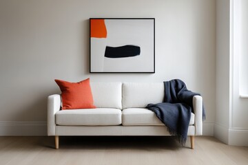 Modern living room interior with off white sofa, orange pillow, and dark blue throw blanket, featuring abstract art
