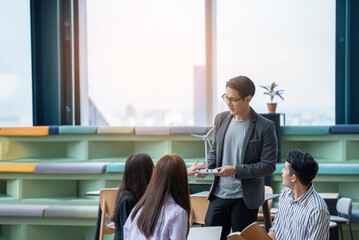 A group of Gen Z Asian business consulting, exchanging information in offices, co-working spaces. © PAPALAH