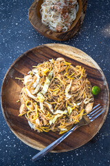 Delicious plate of traditional Filipino Pancit, served on a rustic wooden plate. A slice of calamansi on the side, evoking a sense of authentic Filipino cuisine.