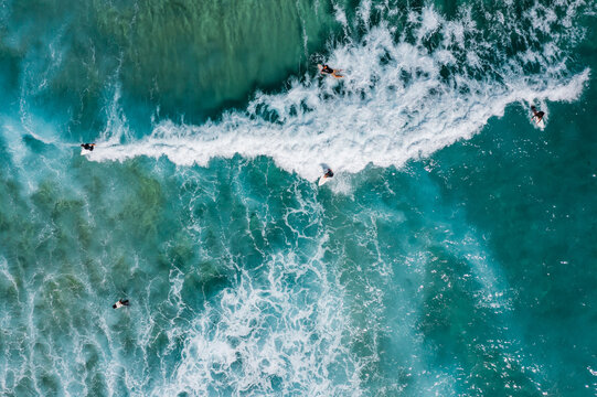 Aerial of surfers riding a wave in the ocean at Bondi beach, Sydney, Australia