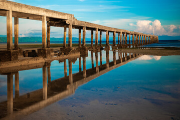 Obraz premium Bridge on a beach where the water is receding