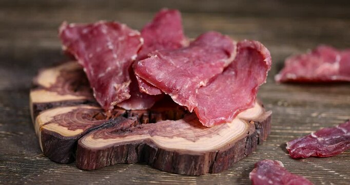 thinly sliced and dried pieces of pork, dried dried meat from a meat tenderloin with spices and salt on a black board