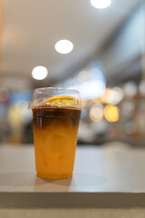 Iced orange Americano black coffee in takeaway cup on the table in cafe