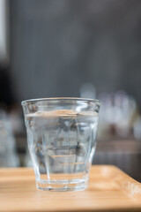 A shot glass of clean cool water with ice. Selective focus and copy space