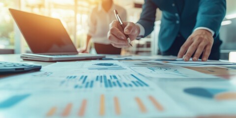 A business executive leads a strategic meeting with documents and laptops spread across the conference table, creating a professional and collaborative atmosphere.