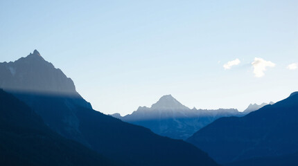 A dramatic mountain landscape with towering peaks and a contrasting play of light and shadows