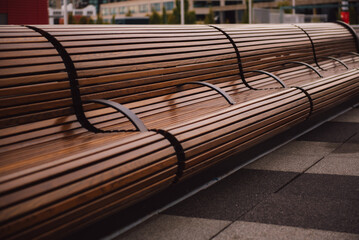 Design of urban public space. Modern long wooden bench in the park.