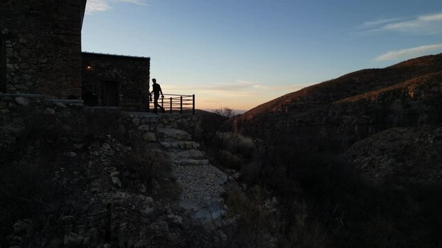 Fotograf&oacute; con un teleobjetivo tomando una fotograf&iacute;a en el atardecer sobre una monta&ntilde;a y un edificio de piedra
