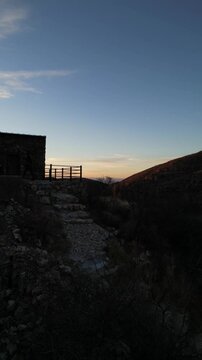 Fotograf&oacute; con un teleobjetivo tomando una fotograf&iacute;a en el atardecer sobre una monta&ntilde;a y un edificio de piedra