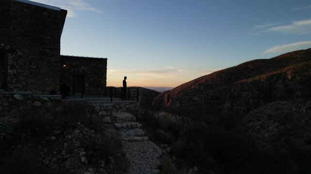 Fotograf&oacute; con un teleobjetivo tomando una fotograf&iacute;a en el atardecer sobre una monta&ntilde;a y un edificio de piedra