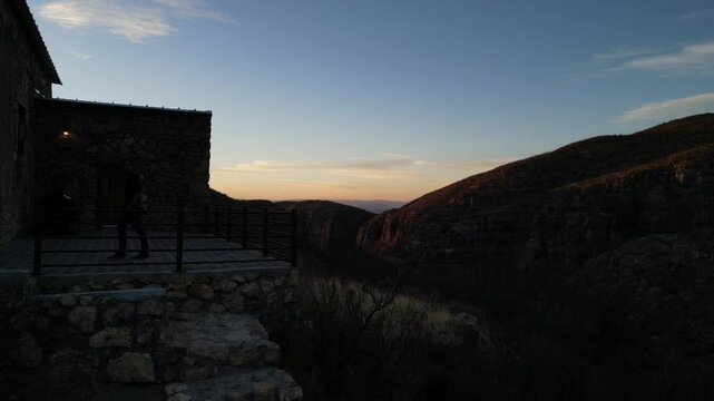 Fotograf&oacute; con un teleobjetivo tomando una fotograf&iacute;a en el atardecer sobre una monta&ntilde;a y un edificio de piedra