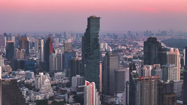 Bangkok high aerial view from the Chao Phraya River to Bang Rak and Si Lom districts at twilight. A large asian capital city with skyscrapers and millions of inhabitants. Cinematic 4k footage