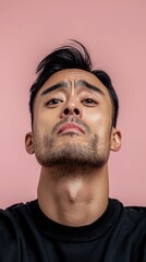 Obraz premium Contemplative Asian Man Serious Face Pink Background Studio Portrait