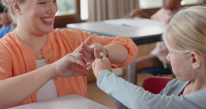 In school, female teacher and student practicing sign language together in classroom