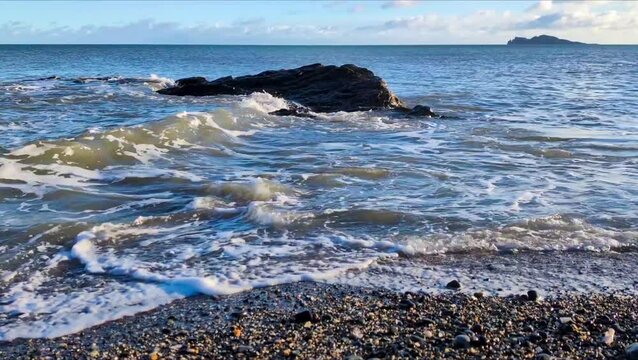 Waves splashes on rock in sea shore: Malahide and Howth beach in Dublin, Ireland Irish sea coastline. 