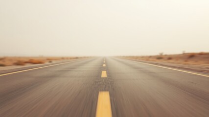 Fototapeta premium A long, straight, paved road disappearing into the distance on a hazy day, with yellow lines marking the lanes and a light brown landscape on either side