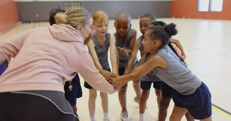 In school gym, children in sportswear cheering together in circle
