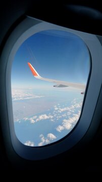 Aerial view of blue sea and sky through a window of an airplane, Travel or sightseeing, Vertical video for smartphone footage