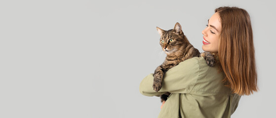 Young woman with cute cat on light background © Pixel-Shot