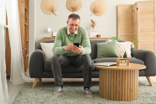 Mature man with mobile phone messaging at home