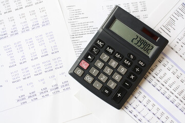 Vintage calculator placed on top of financial spreadsheets, symbolizing traditional accounting, financial analysis, and budgeting. Finance, bookkeeping, data analysis, and business management