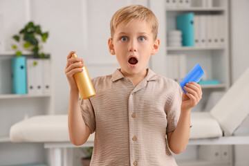 Shocked little boy with head lice comb and remedy for pediculosis in clinic