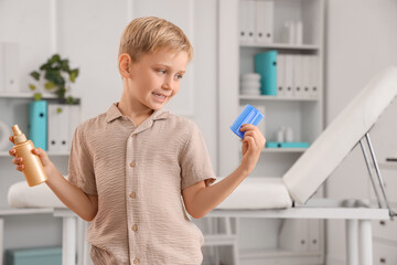 Little boy with head lice comb and remedy for pediculosis in clinic