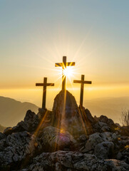 Three crosses on hill with sun rising in background