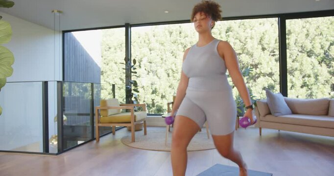 Exercising at home, plus size woman lifting dumbbells on yoga mat, copy space