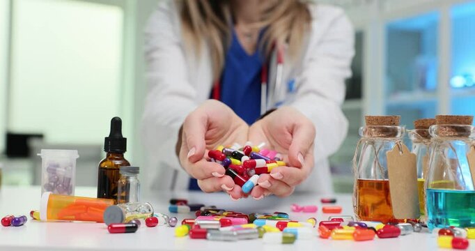 Woman doctor pours multicolor capsules out of handful at desk. Physician prescribes excessive medications during appointment in hospital