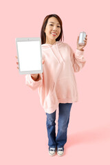 Naklejka premium Young Asian woman with tablet computer and drink on pink background. Mockup for design