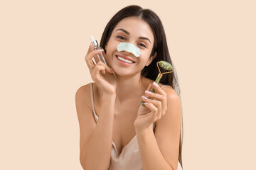 Young woman with nose patch, cosmetic product and massage roller on beige background