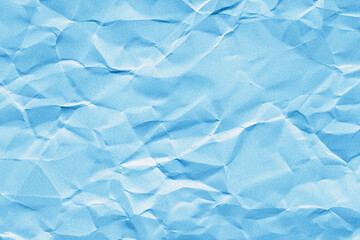 Obraz premium Creased or crumpled blue colored paper background. Wrinkled blank sheet texture with grain or noise