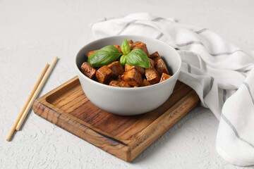 Bowl with pieces of fried tofu cheese and basil on white background