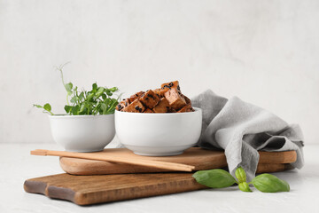 Bowl with pieces of fried tofu cheese, basil and micro green on white background