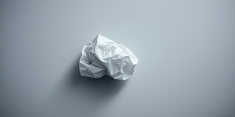 A crumpled piece of white paper against a grey backdrop, capturing the essence of discarded ideas and the potential for new beginnings.