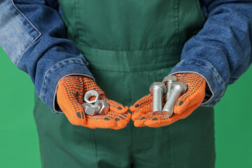 Mechanic with bolts and nuts on green background