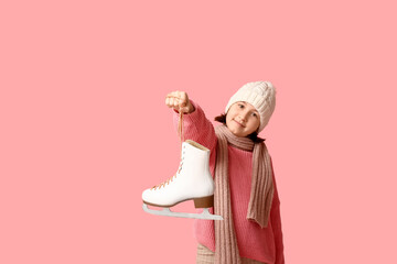 Cute little girl in winter clothes holding ice skate on pink background