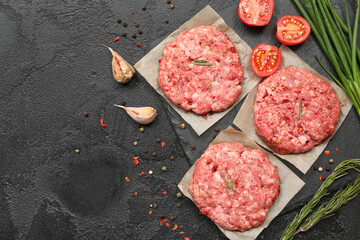 Raw meat cutlets on black textured background