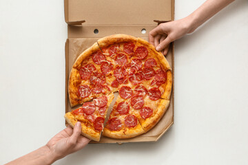 Female hands with cardboard pizza box on white background