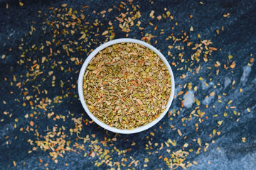 Dried Oregano in a bowl on a dark background. Top view.