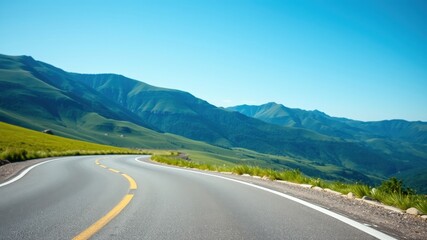 Fototapeta premium A winding asphalt road leads through a picturesque mountain landscape, offering a glimpse of the vast expanse of nature's beauty.