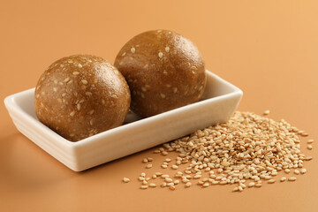 Tilgul Laddu or Til Gul balls for makar sankranti, it's a healthy food made using sesame, crushed peanuts and jaggery. served in a bowl. selective focus showing details.