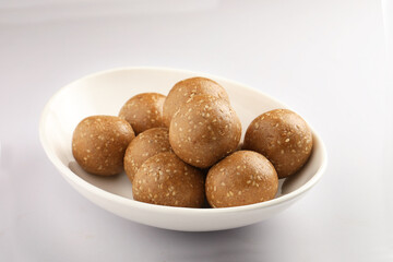 Tilgul Laddu or Til Gul balls for makar sankranti, it's a healthy food made using sesame, crushed peanuts and jaggery. served in a bowl. selective focus showing details.